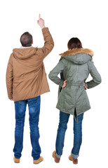 Back view of couple couple in winter jackets pointing.