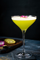 Classic green alcoholic cocktail in a glass with vermouth and gin on a dark wooden background