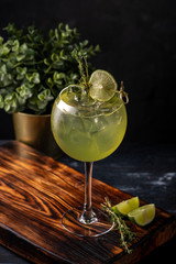 Refreshing Cocktail with Basil Leaf, Lime and ice in a wine glass on a dark background. drink gin and tonic