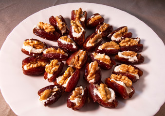 Fresh dates filled with mascarpone cheese and walnuts in a white dish.