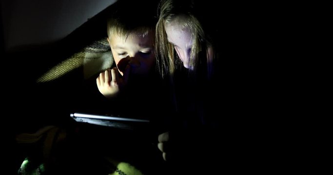 Little girl and boy watching content on her smartphone. The pitfalls of social networks. The childern secretly communicates over the Internet at night. Viewing inappropriate content.