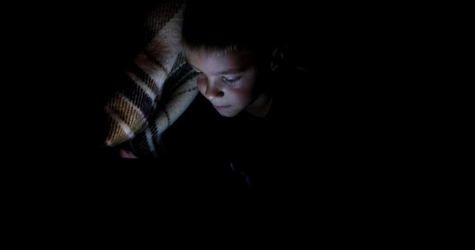 Little boy watching content on her smartphone. The pitfalls of social networks. The childern secretly communicates over the Internet at night. Viewing inappropriate content.