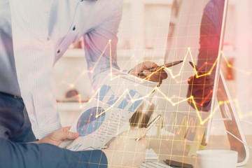 Double exposure of chart with businessman typing on computer in office on background. Concept of...