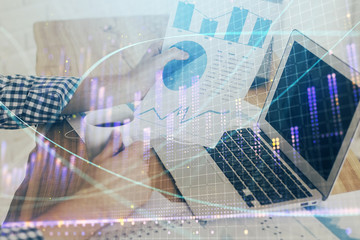 Multi exposure of chart with man typing on computer in office on background. Concept of hard work.