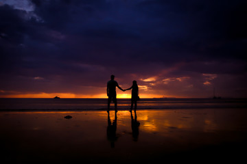 Fototapeta premium Silhouette of couple hold each other hand and Happy Young Couple love on the beach at sunset time