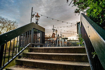  Concrete steps up to an empty riverside beer garden captured at dusk