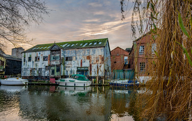 Fototapeta na wymiar The industrial riverside area of Norwich and the waterfront industrial units and boats moored up outside