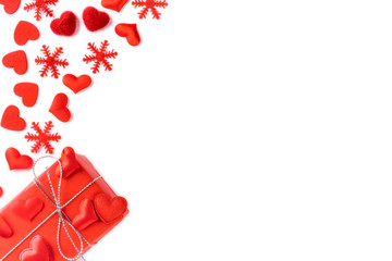 Festive composition from tied red gift box, snowflakes, hearts scattered and isolated on white background, valentines day concept, copy space for text, flatlay
