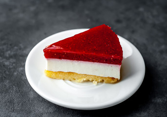 Cheesecake cake with raspberries on a white saucer on a stone background