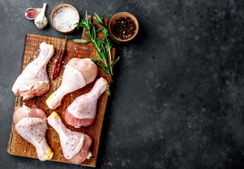 raw chicken legs with spices on a cutting board on a stone background with copy space for your text