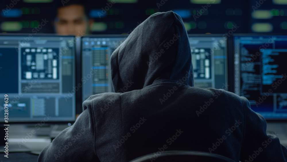 Fototapete Hooded IT Hacker or Specialist Works on a Personal Computer With Display Showing Software Program with Coding Language Interface