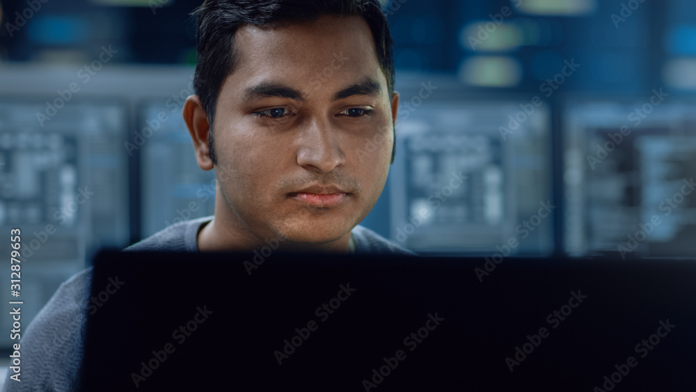 Aufkleber Portrait of a Smart and Handsome IT Specialist Working on a Personal Computer. In the Background Unfocused Personal Computers with Screens in Technologically Advanced Information and Data Center