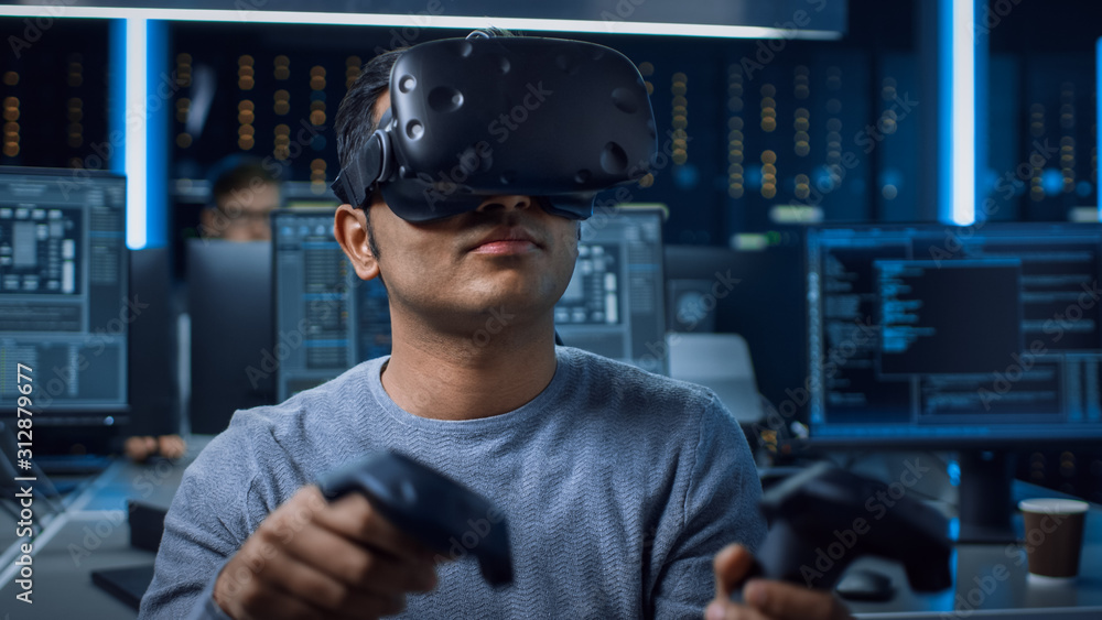 Aufkleber Portrait of Software Delevoper Wearing Virtual Reality Headset Using Controllers to Develop and Program VR Gaming Applications. In Background Technology Developing Studio with Computers and Monitors