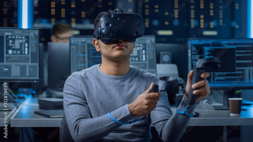 Poster Portrait of Software Delevoper Wearing Virtual Reality Headset Using Controllers to Develop and Program VR Gaming Applications. In Background Technology Developing Studio with Computers and Monitors