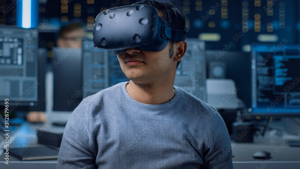 Poster Software Delevoper Wearing Virtual Reality Headset Using Controllers to Develop and Program VR Gaming and Applications. In the Background Technology Developing Studio with Computers and Monitors