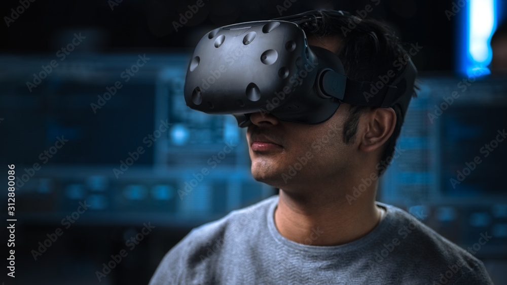 Aufkleber Software Delevoper Wearing Virtual Reality Headset on His Head, Developing and Programming VR Game or Application. In the Background Technology Developing Studio with Computers and Monitors