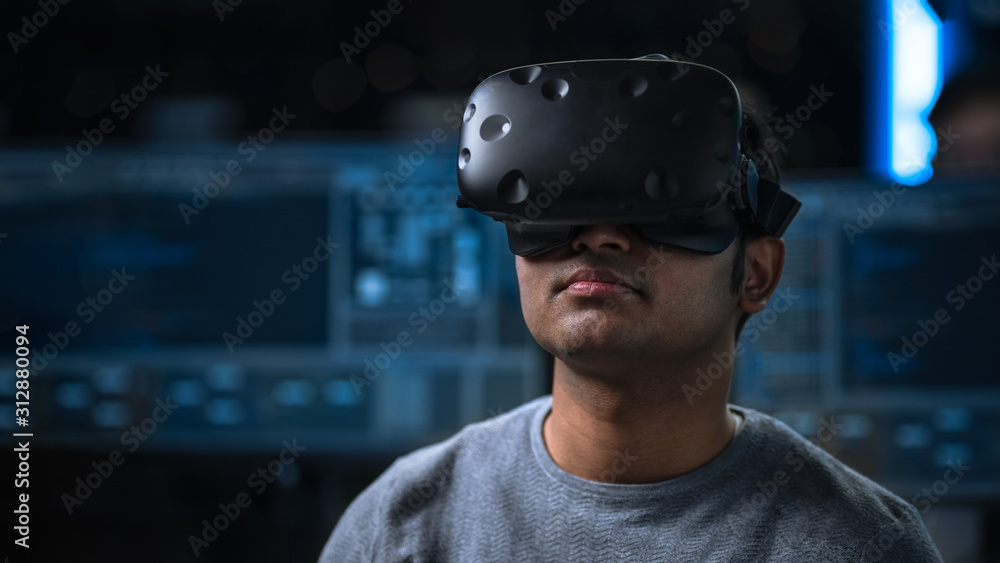 Aufkleber Software Delevoper Wearing Virtual Reality Headset on His Head, Developing and Programming VR Game or Application. In the Background Technology Developing Studio with Computers and Monitors