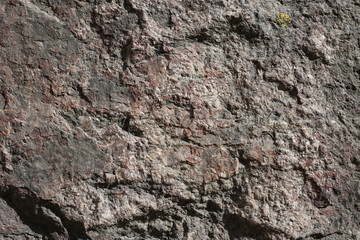 Closeup of a big stone in red, orange and black tones. In this photo you can see the rustic texture of a rock in detail. Perfect background image. Photographed in Finland's nature during summer day.