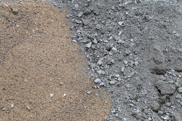 Construction materials in a construction site. In this photo you can see brown sand and grey crushed grey stone material. Closeup color image with beautiful textures.
