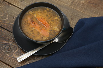 fish soup in a bowl on a wooden rustic background and a tissue napkin and spoon. The Mediterranean...