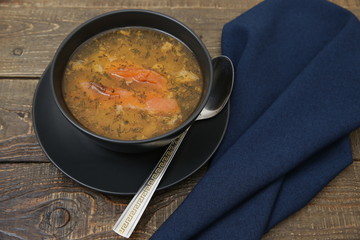 salmon fish soup in a bowl on a wooden rustic background and fabric napkin and spoon. The Mediterranean or vegetarian diet.