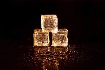 Golden ice cubes on black background.
