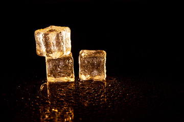Golden ice cubes on black background.