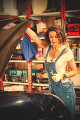 beautiful woman in a jeans jumpsuit of a car mechanic opened the bonnet cover