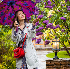 woman with an umbrella in her hands walks in the spring rainy garden