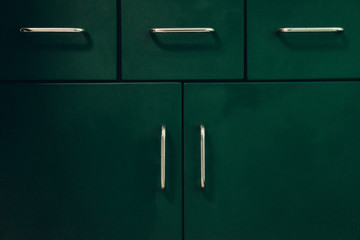 Retro kitchen of emerald color, drawer with metal handles. Kitchen trends.  The main subject is out of focus, film and grain photo