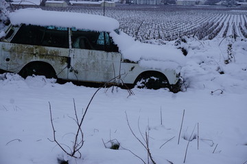 abandoned car in the snow by the vineyard in the Loire valley, France