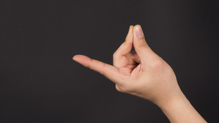 Male model is doing snap gesture hand sign on black background.