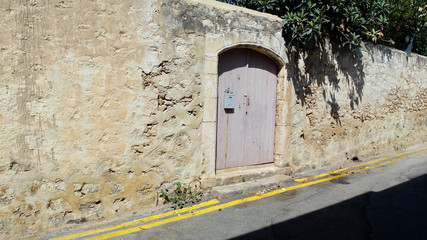 old door in the stone wall by the road