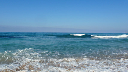 shore of the blue sea, soft waves, white foam, clear sky