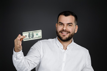 Portrait of young man holding money banknotes isolated on black background