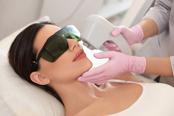 Obraz na płótnie Canvas Young woman undergoing laser epilation procedure in beauty salon
