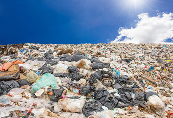 garbage dump pile in trash dump or landfill,truck is dumping the gabage from municipal,garbage dump pile and blue sky background with flare from sun ,pollution concept