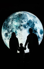 Silhouette picture of a family stands on the mountain with A big full moon at night.