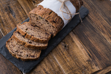 Sliced vegan homemade  banana bread with nuts and berry in the baking paper on the wooden table, selective focus.  cinnamon, anis stars around.
