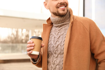 Man with cup of coffee on city street in morning, closeup