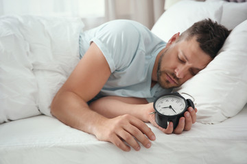 Obraz na płótnie Canvas Man sleeping with alarm clock at home in morning