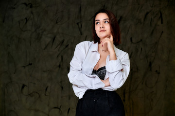 Portrait of a pretty smiling brunette Caucasian female student girl in a white shirt on a gray background. Standing right in front of the camera in various poses.