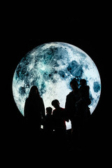 Silhouette picture of a family stands on the mountain with A big full moon at night.