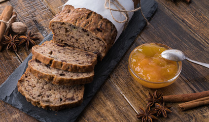 Sliced vegan homemade  banana bread with nuts and berry in the baking paper on the wooden table, selective focus.  cinnamon, anis stars around.
