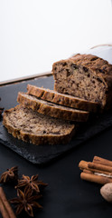 Sliced vegan homemade  banana bread with nuts and berry in the baking paper on the wooden table, selective focus.  cinnamon, anis stars around.