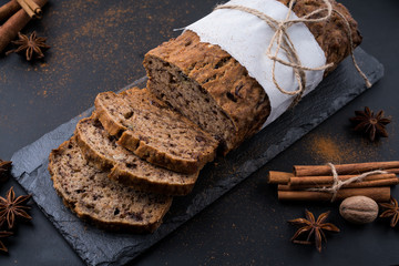 Sliced vegan homemade  banana bread with nuts and berry in the baking paper on the wooden table, selective focus.  cinnamon, anis stars around.