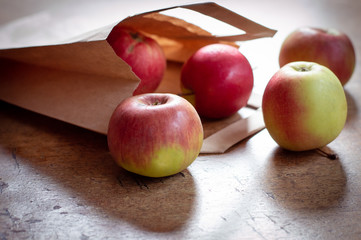 Red healthy apples pouring out of paper shopping bag