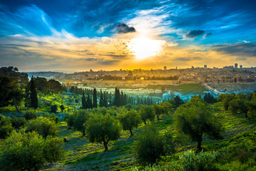 Beautiful sunset clouds over the Old City Jerusalem with Dome of the Rock, the Golden/Mercy Gate and St. Stephen's/Lions Gate; view from the Mount of Olives with olive trees in the foreground