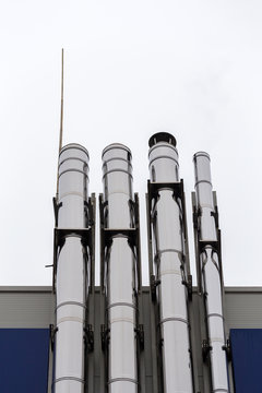 Chrome ventilation pipes on the outside wall of the white and blue Industrial building