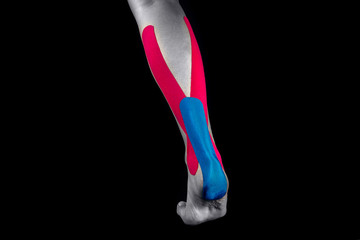 Medical taping for calf pain relief isolated on black background. - 312894074